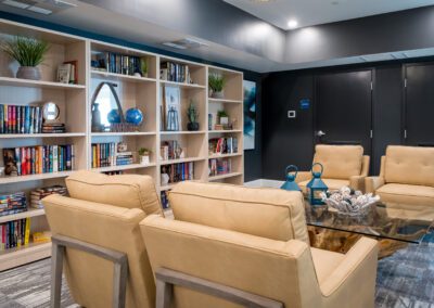 Prime Carolina Coast's library room with floor-to-ceiling shelves filled with books and four large tan armchairs for reading