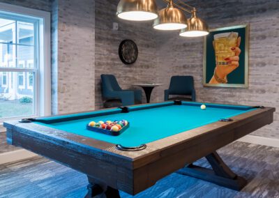 The green-carpeted billiard table in Prime Carolina Coast's game room