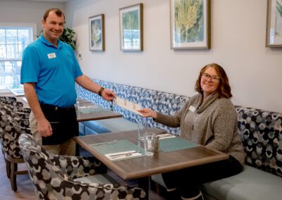 A friendly member of Prime Carolina Coast's team offers a menu to a diner