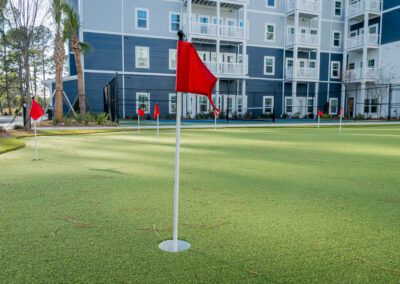 A hole on the putting green waits with a red flag in it.