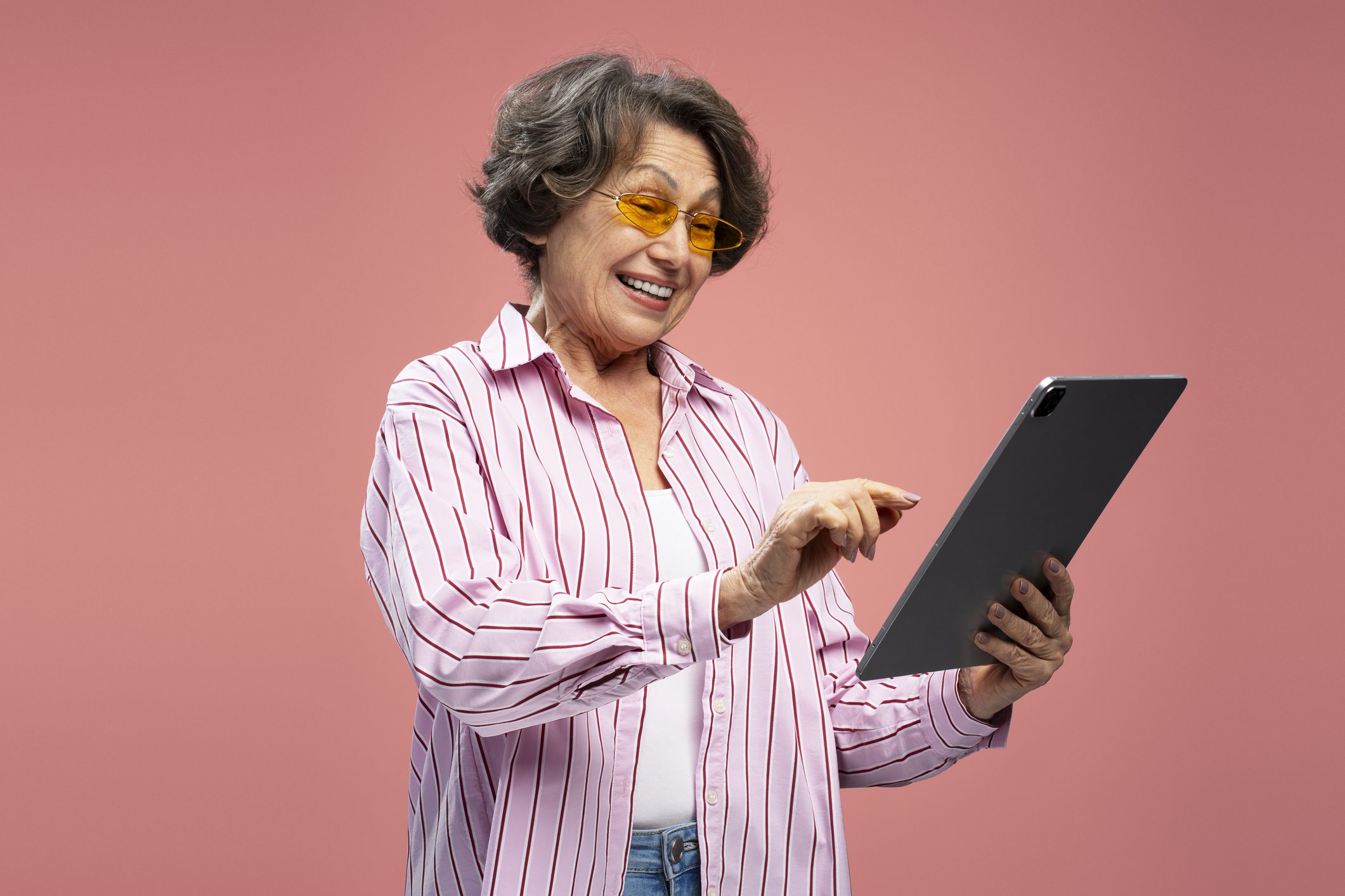 Excited senior woman holding a tablet