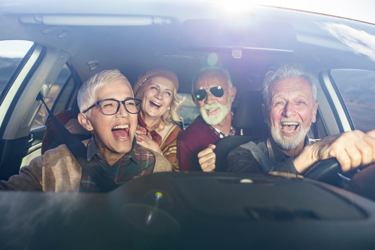 Group of happy seniors having fun on a road trip in a car. seniors driving together