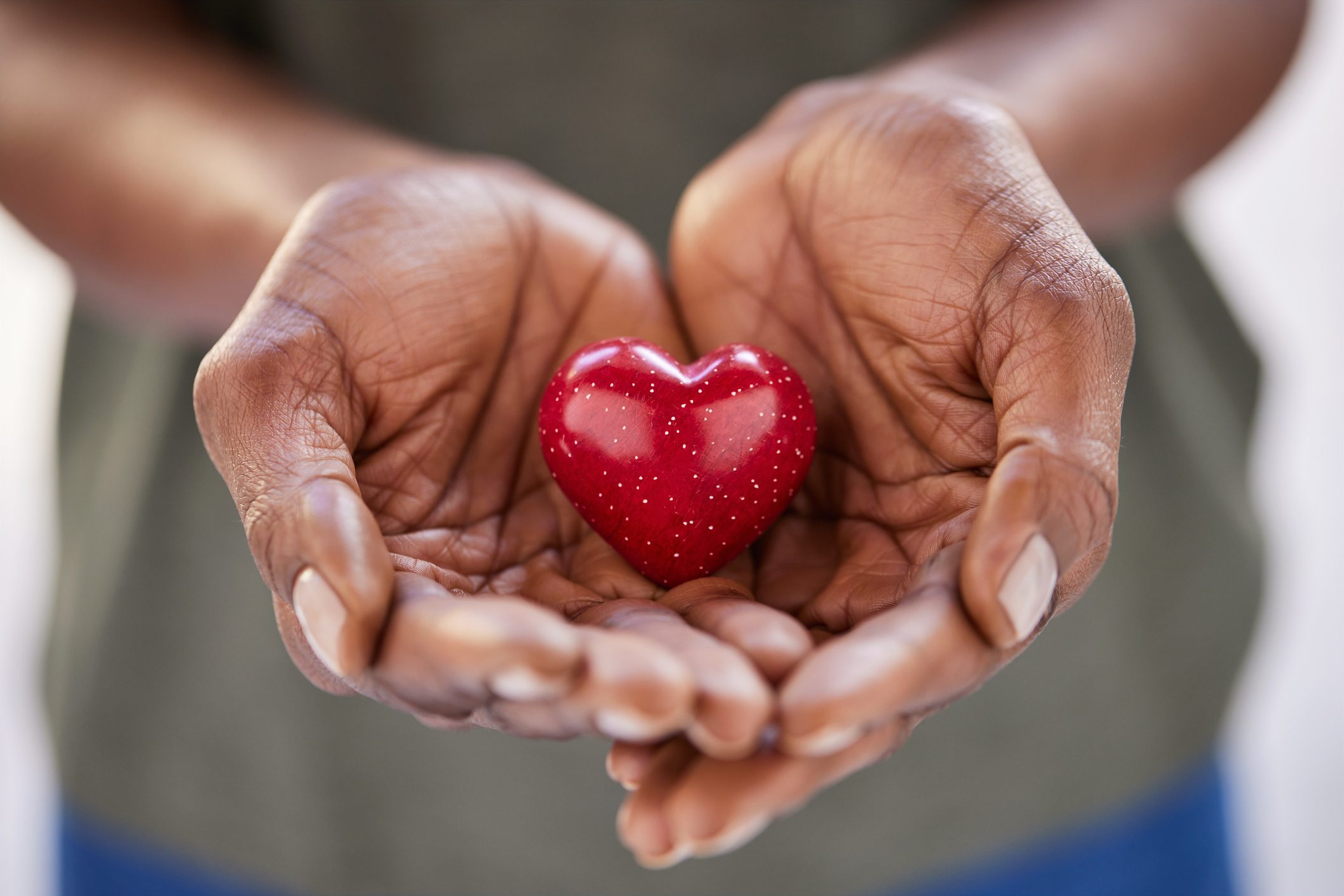 Close up of african woman hands holding red heart in solidarity heart in palm of hands