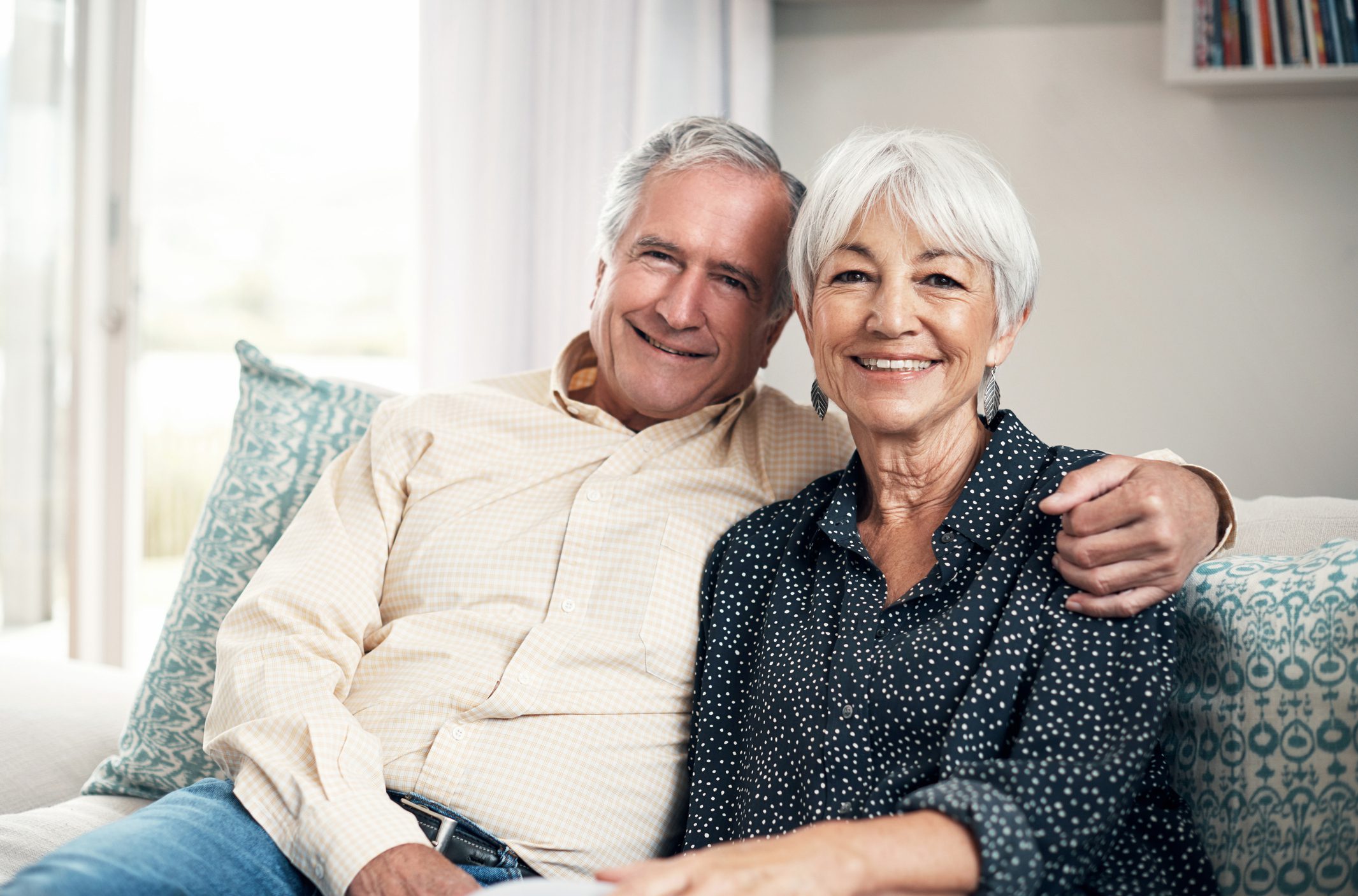 Senior couple at home relaxing together on sofa and smiling