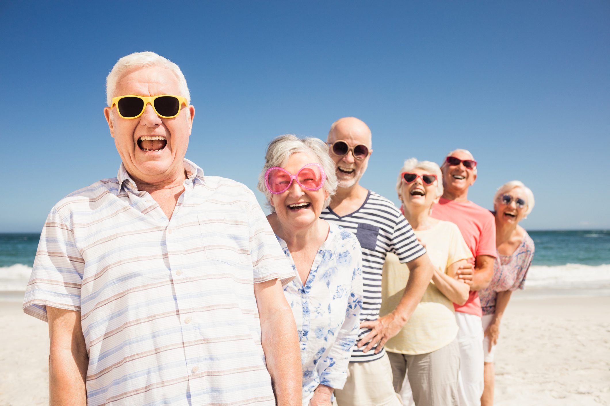 A group of smiling senior adults at the beach.