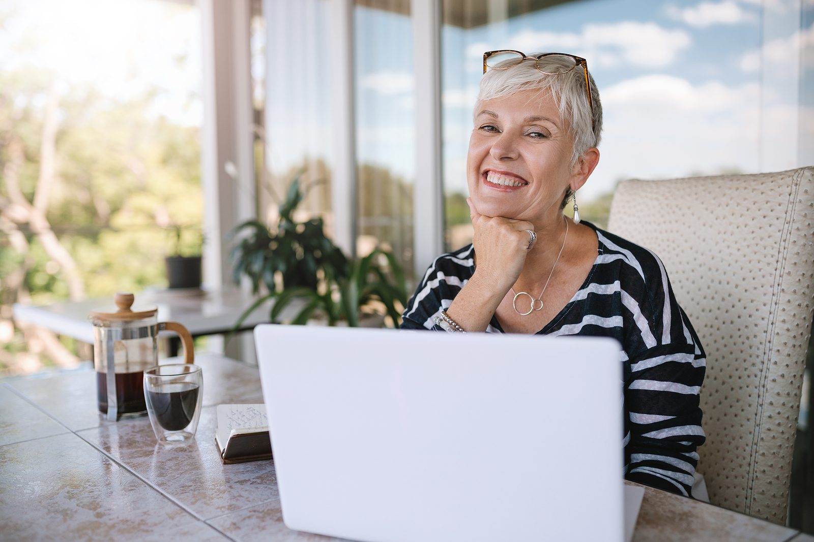 Beautiful Senior Woman Using Laptop At Home. Mature Smiling Woma Woman using a computer on a balcony