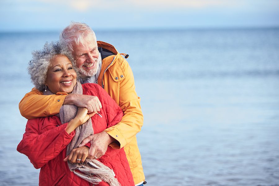 Senior couple hugging along the shoreline during winter